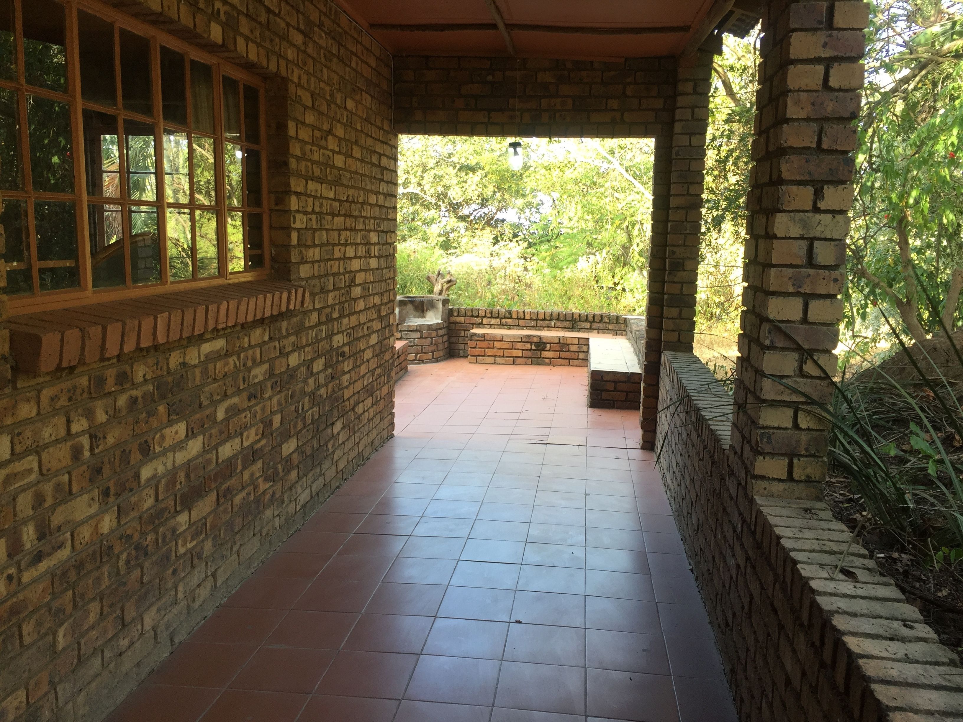 A covered patio area with brick walls and tiled flooring.