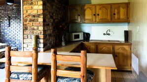 A kitchen with wooden cabinets, a microwave, and a sink. - Masasana's Rest (Mbombela)