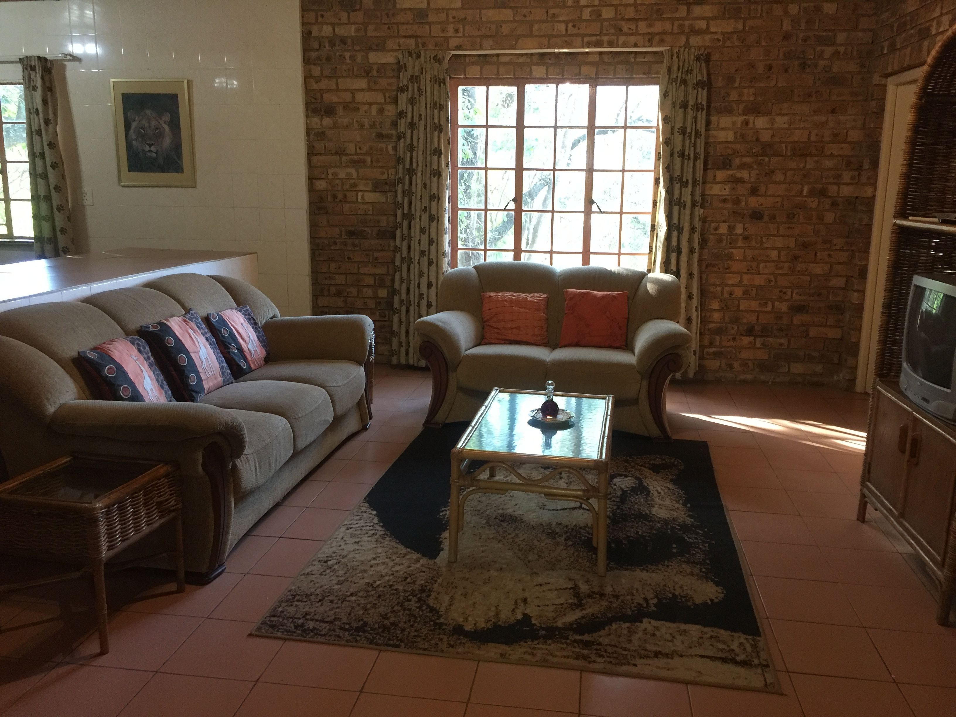 A living room with a brick wall, two sofas, a coffee table, and a television.