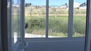 Een raam met uitzicht op een groen landschap en gebouwen in de verte.