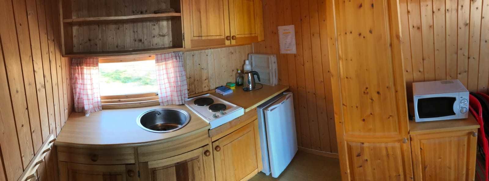 Una cocina compacta con armarios de madera, un lavamanos, una estufa, un refrigerador y un microondas.