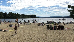 A beach with people, tents, and a lake in the background. - O'Lin Lake Resort (Hole)
