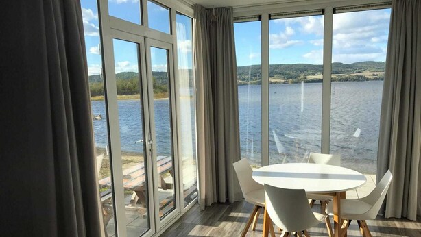A room with large windows overlooking a lake, a round table with chairs, and a checkered floor. - O'Lin Lake Resort (Hole)