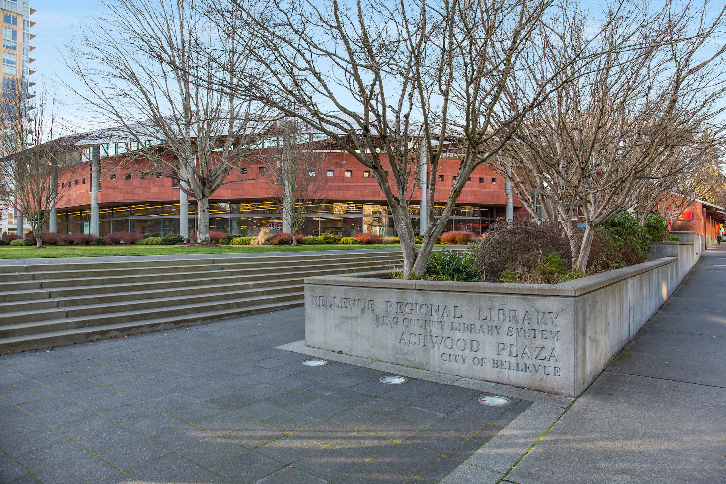 A stone bench with a plaque reading "Bellevue Regional Library King County Library System Ashwood Plaza City of Bellevue."