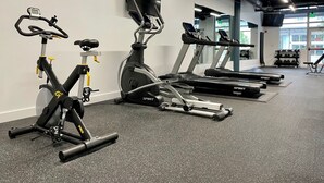 A gym with stationary bikes, treadmills, and a wall-mounted TV. - Kasa Bellevue Seattle (Bellevue)