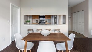 A modern kitchen with a central island, white chairs, and a wooden dining table. - Kasa Bellevue Seattle (Bellevue)