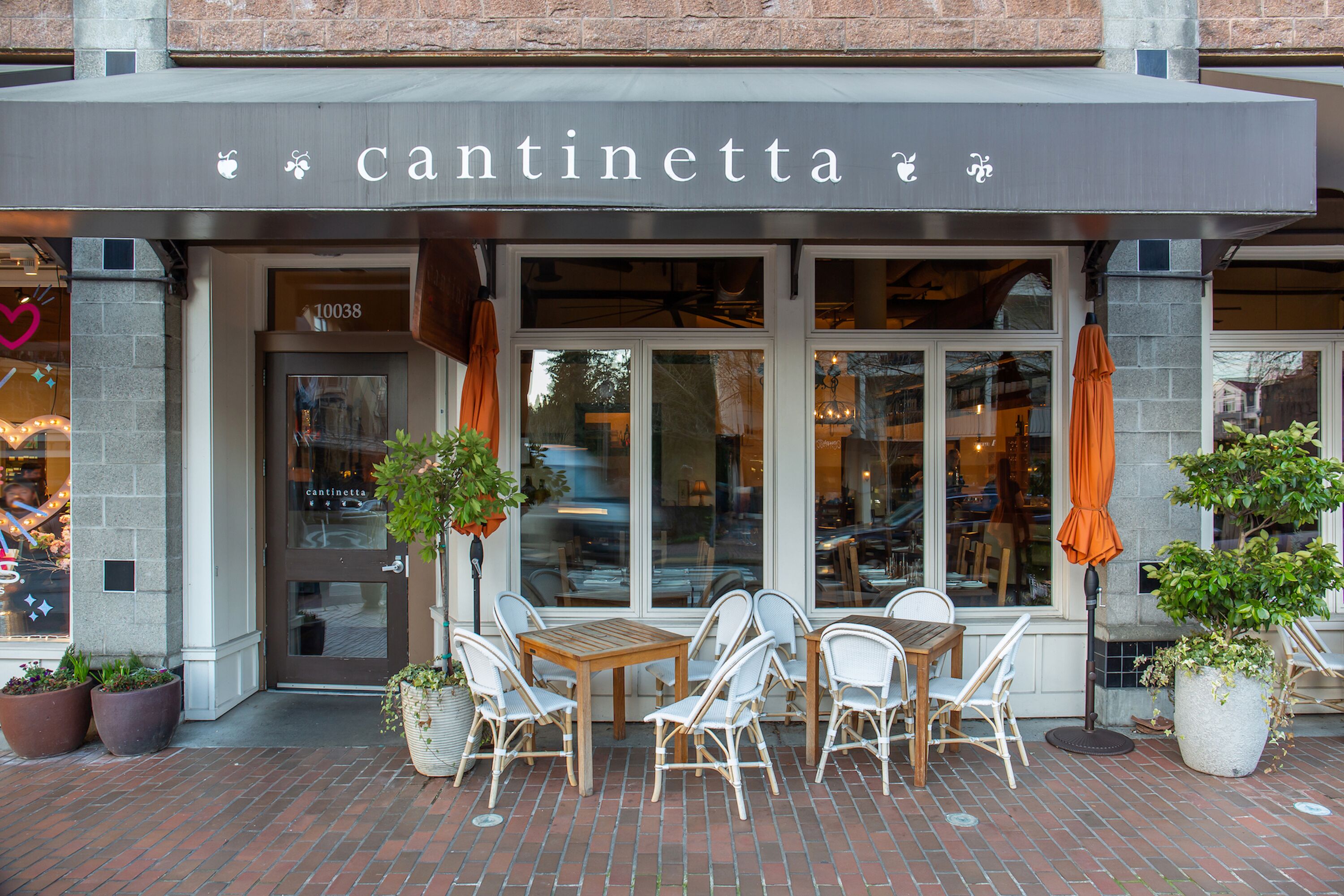 A storefront with the name "cantinetta" above the entrance, featuring a brick-paved patio with outdoor seating and potted plants.
