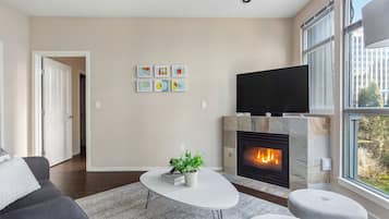 A modern living room with a fireplace, a flat-screen TV, and a sofa.