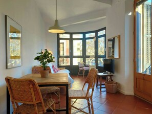 A dining area with a table, chairs, a hanging light, and a large window with multiple panes.