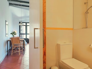 Un bagno con il water, una doccia e uno stipite di legno.