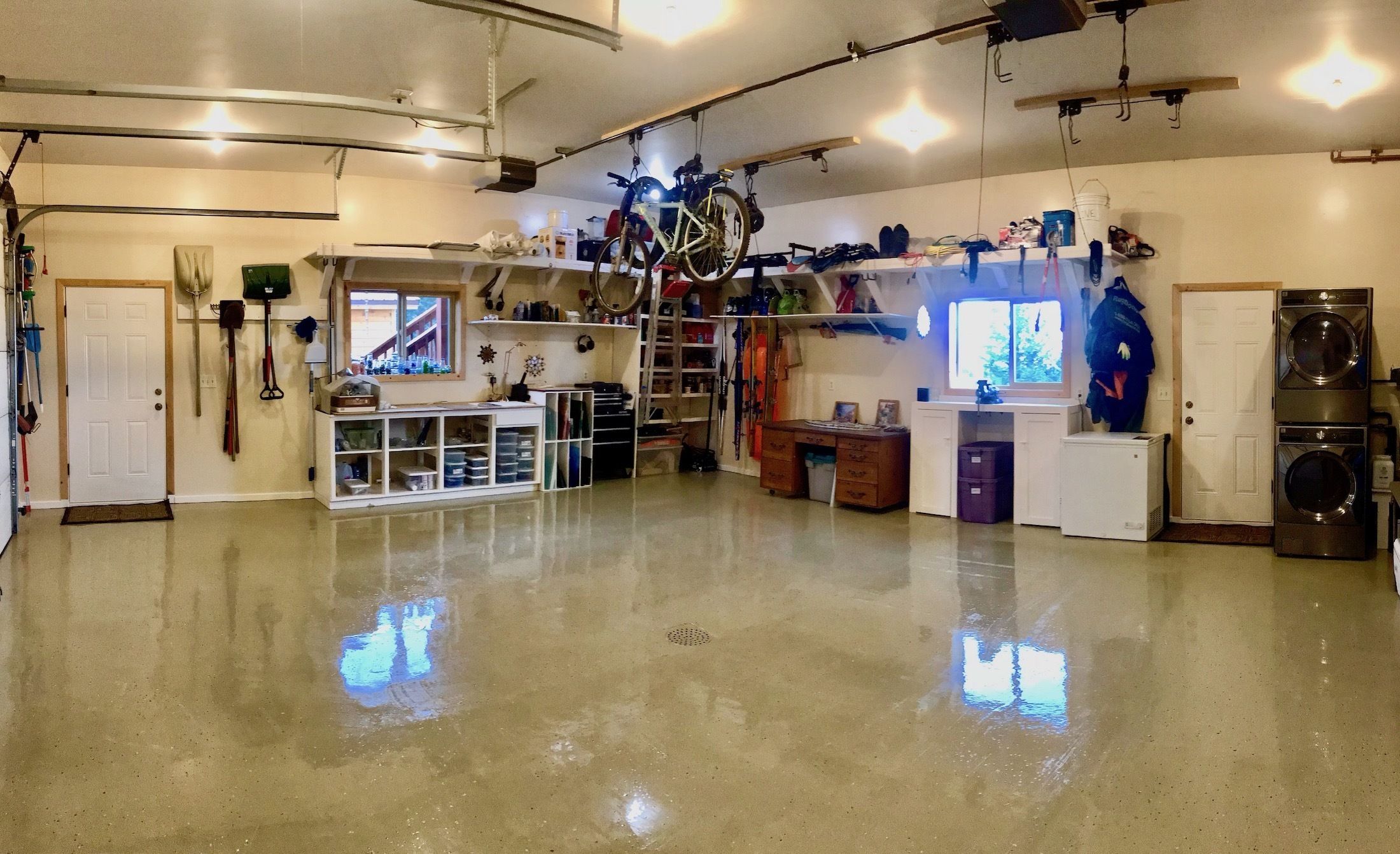 A spacious garage with a polished concrete floor, various tools, a bicycle, and a laundry area.