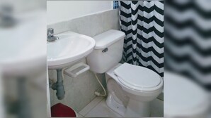 Une salle de bain avec un lavabo blanc, des toilettes et un rideau de douche à motifs zigzag noir et blanc.