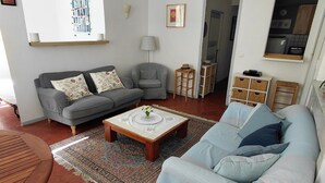 Ein Wohnzimmer mit Sofa, Sessel, Couchtisch und Teppich.