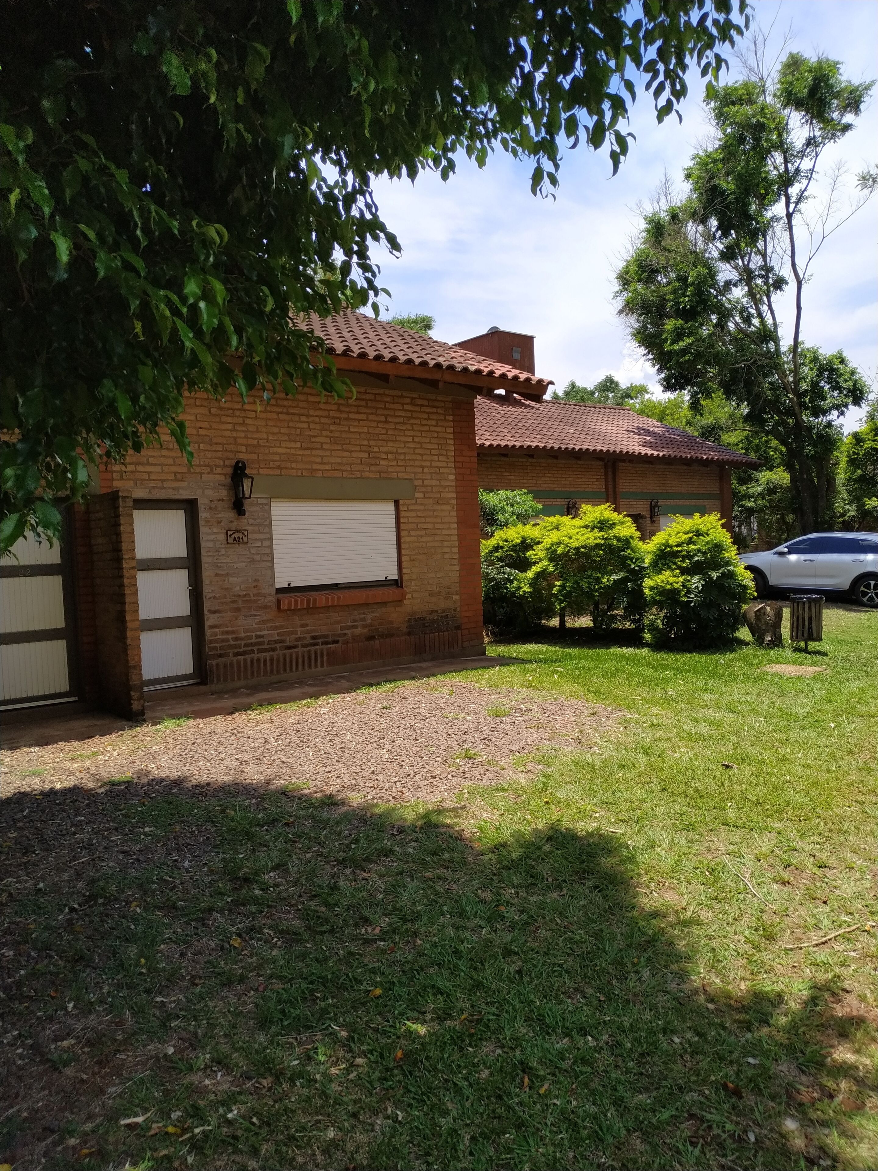 Una casa de ladrillo de dos pisos con garaje, entrada cubierta y césped bien cuidado.