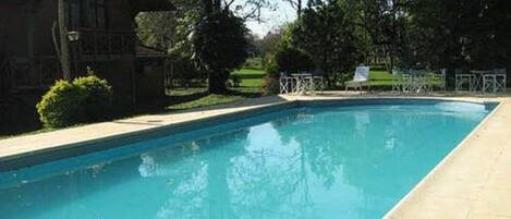 A rectangular swimming pool with a clear blue water surface, surrounded by a paved deck.
