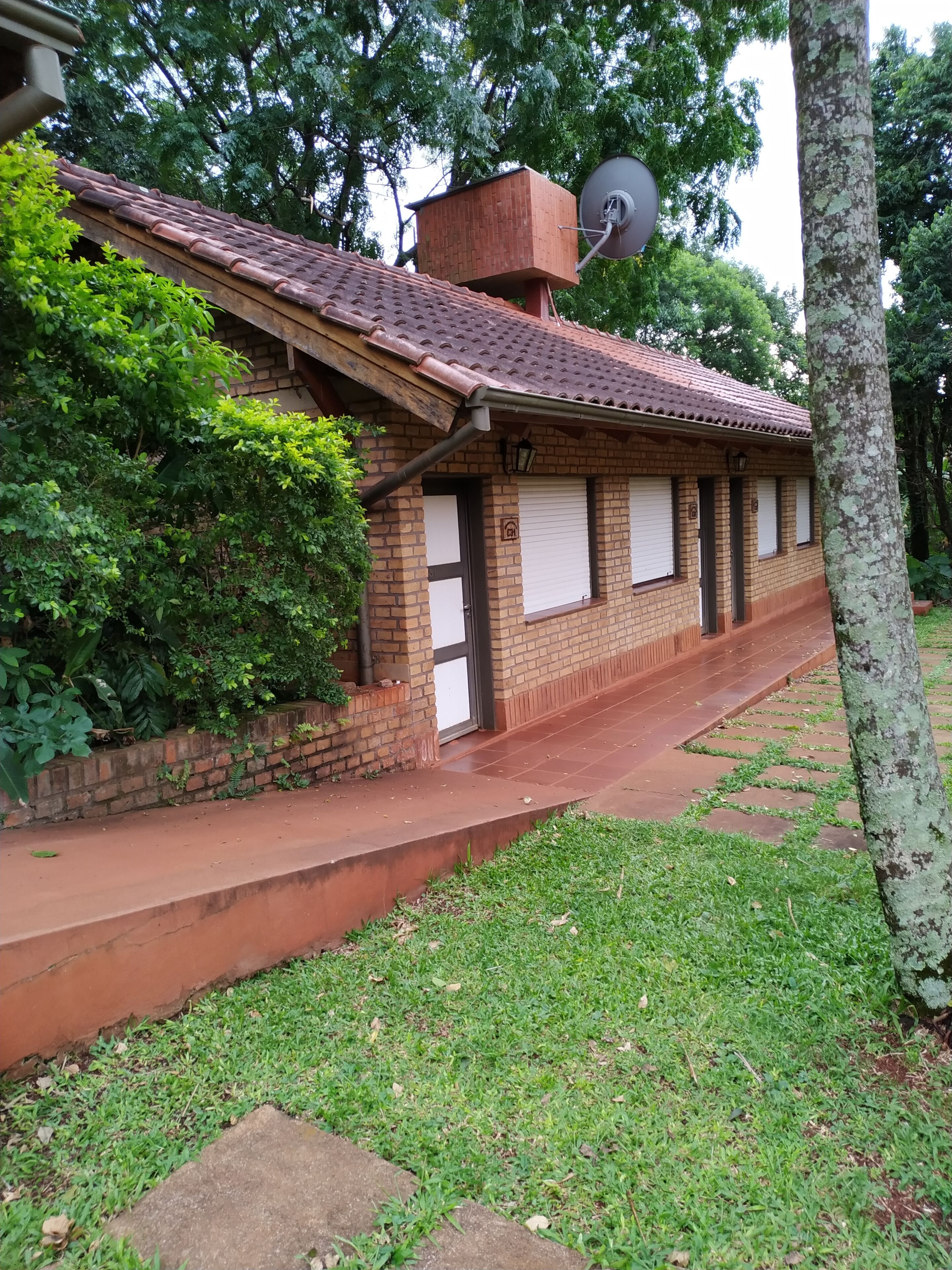 A brick building with a tiled roof, a satellite dish, and a small satellite dish on the roof.