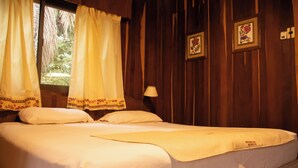 A bed with white linens, a bedside lamp, and a window with curtains. - Hotel Cabanas del Parque (Obera)