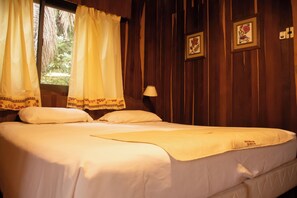 A bed with white linens, a bedside lamp, and a window with curtains. - Hotel Cabanas del Parque (Obera)
