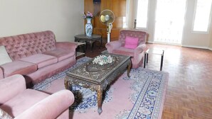 Una sala de estar con un sofá rosa, un sillón a juego, una mesa de centro con diseño y un jarrón decorativo.