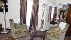 Sala de estar con dos sillones, una mesa de centro, una lámpara de pie y un espejo.