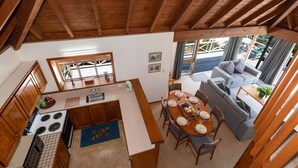 A compact kitchen with a dining area, wooden beams, and a view to the outside. - Te Maiki Escape - Russell Holiday Home (Russell)