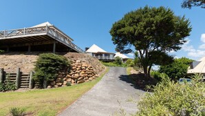 A pathway leading to a building with a wooden deck and a stone wall. - Te Maiki Escape - Russell Holiday Home (Russell)