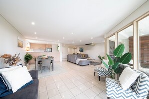 A spacious living area with a sofa, armchairs, and a dining table. - Phil's Place on Airlie (Airlie Beach)
