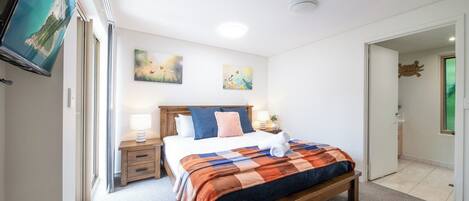 Ein Schlafzimmer mit einem Bett, Nachttischen, einem Flachbildfernseher und Kunstwerken an der Wand.