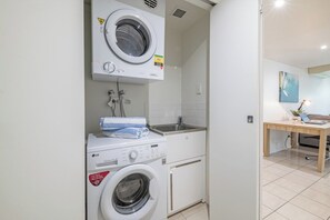 Un área de lavandería compacta con lavadoras apiladas y un lavamanos.
