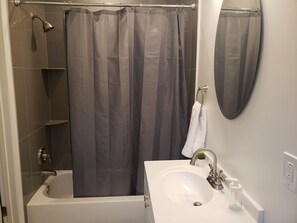 A bathroom with a bathtub, a shower curtain, a sink with a faucet, and a mirror. - Large house perfect for large families! Off Street Parking for 2 cars (Washington)