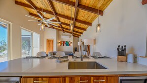 A modern kitchen with a large island, wooden ceiling beams, and a built-in dishwasher. - Villa Topaz Guest Villa Above West Bay With 180 Degree Views @ Villa Topaz (West Bay)