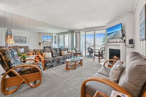 A spacious living room with a large sofa, two armchairs, a coffee table, and a fireplace. - Charming Upper Beachfront Cottage-Breathtaking Ocean Views-D8 North Coast Village (Oceanside)