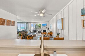 A spacious living room with a view of the beach, a ceiling fan, and a fireplace. - Charming Upper Beachfront Cottage-Breathtaking Ocean Views-D8 North Coast Village (Oceanside)