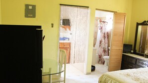 A bedroom with a bed, a chair, a desk, and a wardrobe. - Belle Air Paradise JM (Runaway Bay)