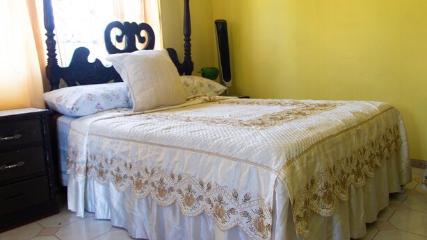 A bedroom with a four-poster bed, a nightstand, and a dresser. - Belle Air Paradise JM (Runaway Bay)