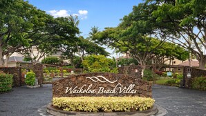 Naamplaatje voor Waikoloa Beach Villas, met een stenen basis en een bloemenrand.