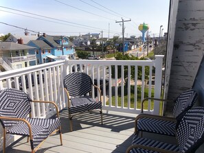 A balcony with wicker chairs and a view of a town with houses and a water tower. - Downtown OC, Water views! (Ocean City)