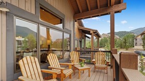 A wooden deck with Adirondack chairs and a table, overlooking a mountainous landscape. - Luxury Townhome w/ Gorgeous Slope Views and Close to Gondola, Shops & Dining! (Keystone)