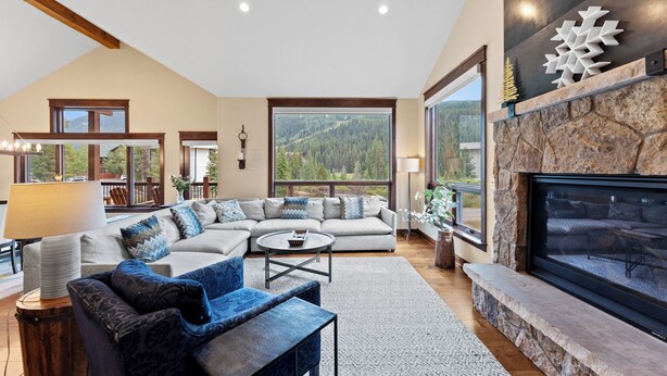 A spacious living room with a large sectional sofa, a fireplace, and a view of a mountainous landscape through large windows. - Luxury Townhome w/ Gorgeous Slope Views and Close to Gondola, Shops & Dining! (Keystone)