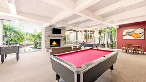 Une table de billard, une cheminée et un coin repas avec vue sur la verdure.
