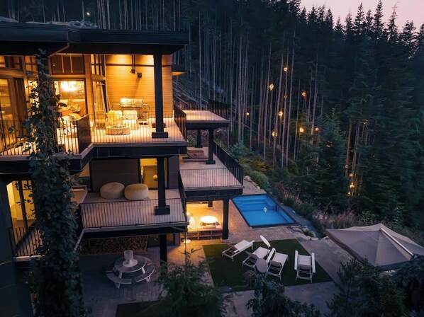Uma casa com vários níveis, piscina, área de estar externa e um terraço.