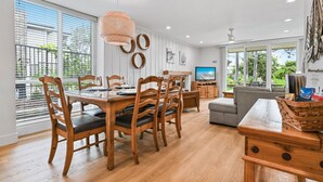 Ein moderner Essbereich mit Holztisch und Stühlen, einem Fernseher und einer Couch.