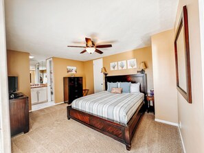 A bedroom with a bed, a ceiling fan, a dresser, a vanity, and a television. - Upscale 2 Story Penthouse- Beautiful Tropical garden and ocean views  - G322 North Coast Village (Oceanside)