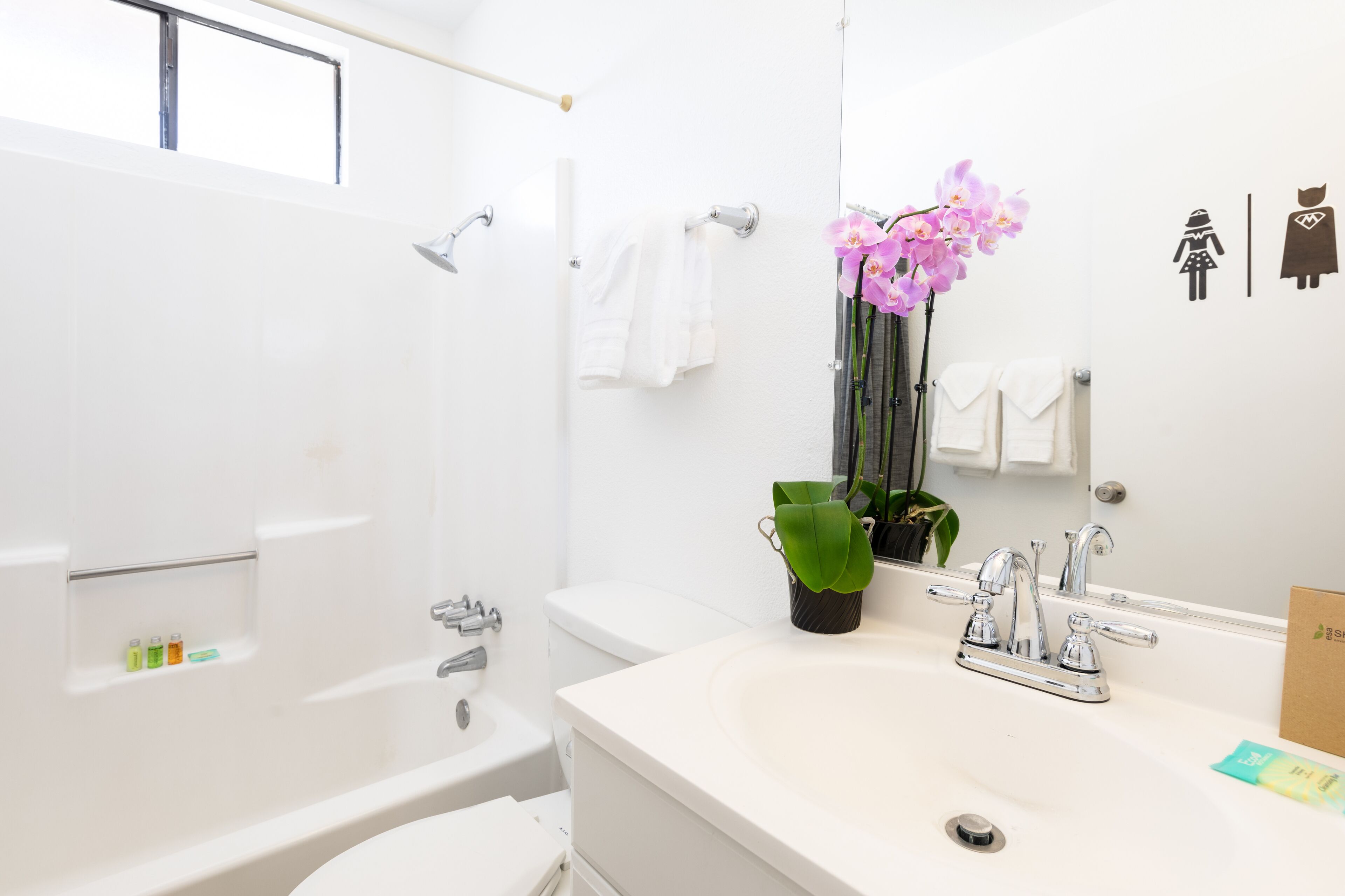 A modern bathroom with a white sink, a mirror, and a shower area.