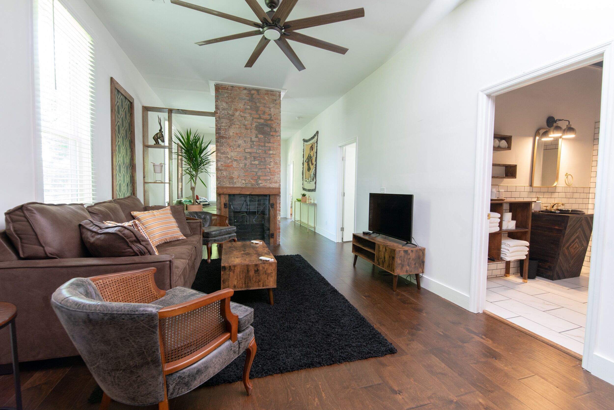 Un salon avec une cheminée, un téléviseur et un ventilateur de plafond.