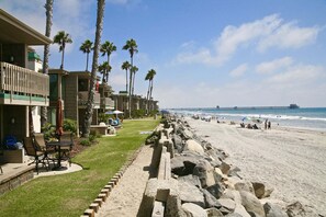 A beachfront hotel with a pool, palm trees, and a pier in the background. - Upper Beachfront-Steps From Water's Edge-D28 North Coast Village (Oceanside)