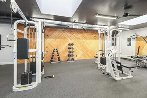A gym with various exercise equipment, a wooden wall, and a ceiling with a skylight.