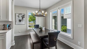 A dining area with a dark wooden table, a chandelier, and a black chair. - Rooftop Style · Fire Pit · Wet Bar · Skyline Views (Nashville)