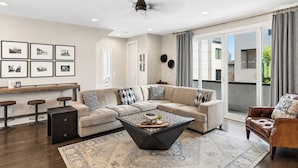 A modern living room with a sectional sofa, a coffee table, and a view of the outdoors. - Rooftop Style · Fire Pit · Wet Bar · Skyline Views (Nashville)