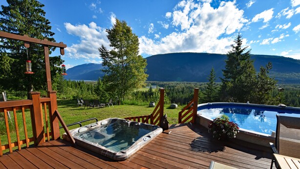 A wooden deck with a hot tub and seating, overlooking a mountainous landscape. - Pool;wilderness; view of mountains, lake, river;hot tub, sauna;privacy;hiking! (Argenta)